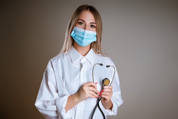 Jovem médica de uniforme usando máscara