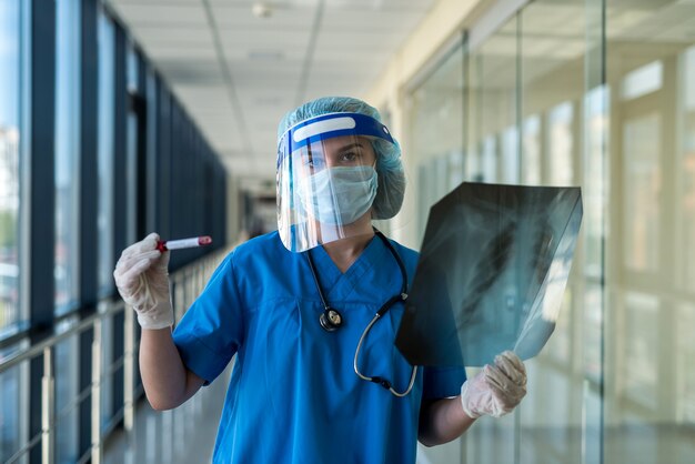 Jovem médica em luvas segurando um tubo com sangue de teste covid-19 na clínica. resultado de teste positivo