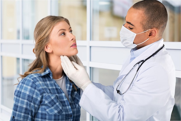 Foto jovem médica está examinando o rosto do paciente sobre branco