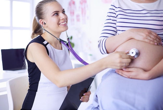 Jovem médica examinando mulher grávida na clínica