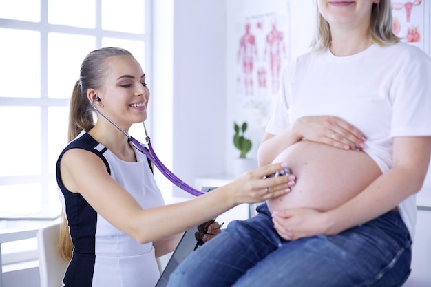 Jovem médica examinando mulher grávida na clínica