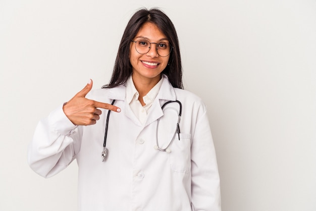 Jovem médica latina isolada em um fundo branco pessoa apontando com a mão para um espaço de cópia de camisa, orgulhosa e confiante