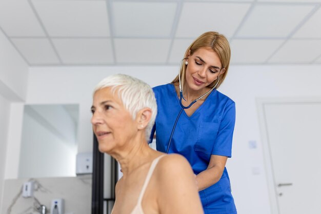 Jovem médica ouve o peito do coração do paciente sênior com estetoscópio na reunião clínica Mulher GP checkup examina cliente mulher com conceito de saúde estetoscópio