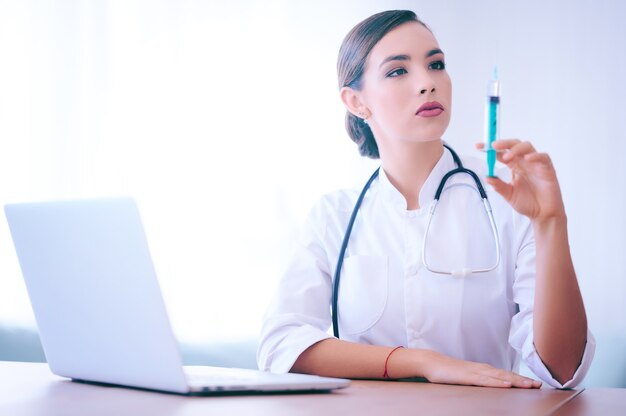 Jovem médica segura uma seringa. Enfermeira no hospital. Trabalhador médico.