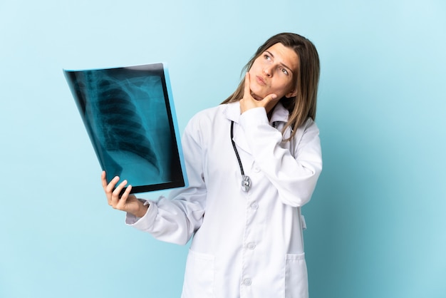 Jovem médica segurando uma radiografia isolada, tendo dúvidas