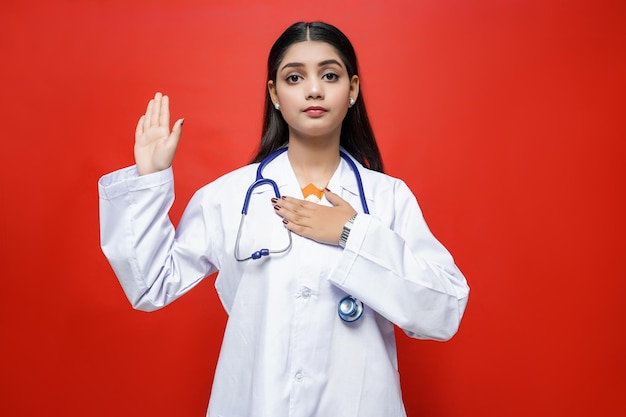 jovem médica vista frontal usando casaco e estetoscópio em volta do pescoço modelo indiano do paquistanês