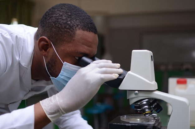 Jovem médico africano bonito analisando amostra de um experimento em seu laboratório