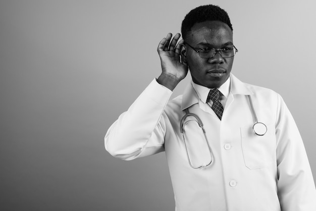 jovem médico africano usando óculos contra uma parede branca. Preto e branco