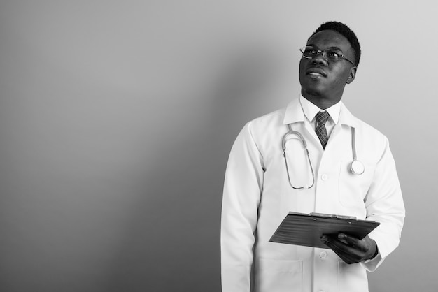 Foto jovem médico africano usando óculos contra uma parede branca. preto e branco