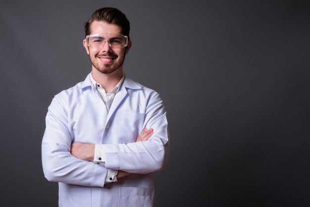 Foto jovem médico barbudo bonito usando óculos de proteção