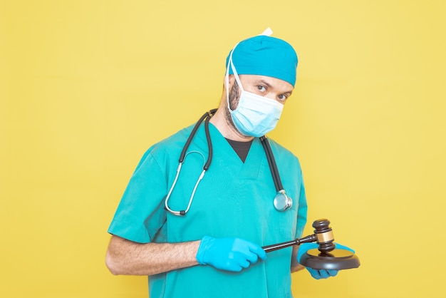 Jovem médico cirurgião vestido de verde sobre fundo amarelo