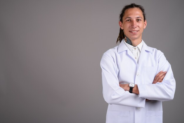 Jovem médico com dreadlocks contra um fundo cinza