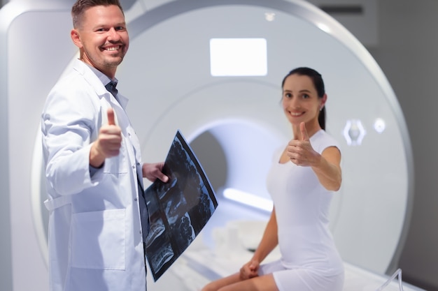 Foto jovem médico e paciente segurando o polegar na sala de ressonância magnética da sala de ressonância magnética