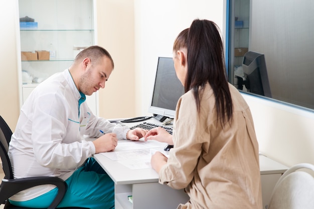 Jovem médico examinando e consultando a paciente jovem na clínica do hospital. profissional