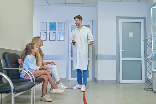 Foto jovem médico falando com os pacientes no salão da clínica