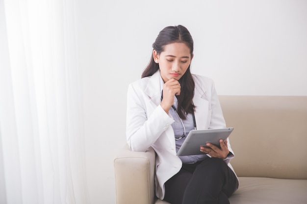 Jovem médico feminino asiático lendo algo sobre o tablet pc