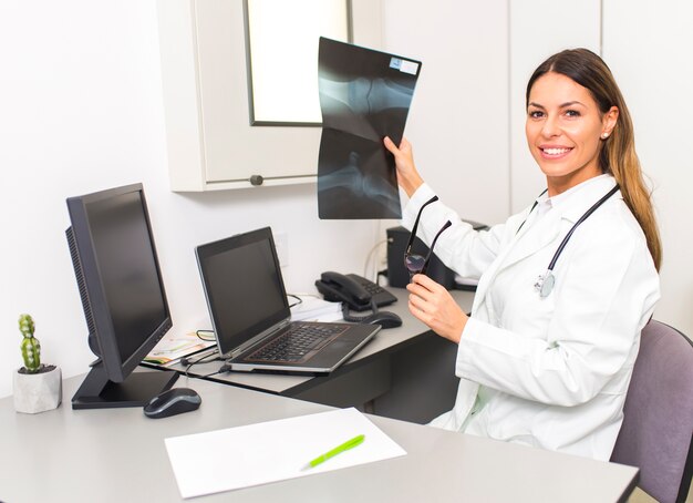 Jovem médico feminino olhando a imagem de raio-x do paciente no hospital