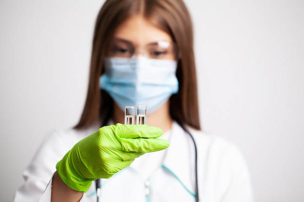 Jovem médico feminino segurando tubos de ensaio com vacina