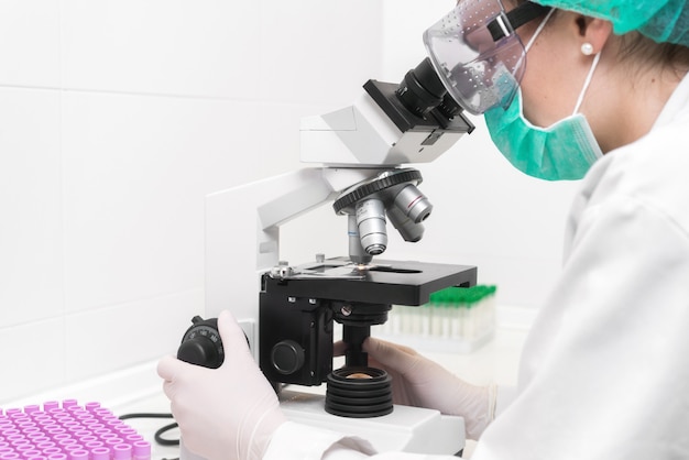 Jovem médico feminino trabalhando com um microscópio em um laboratório