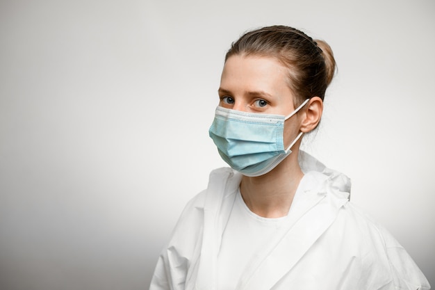 Jovem médico feminino vestindo traje de proteção e máscara médica.