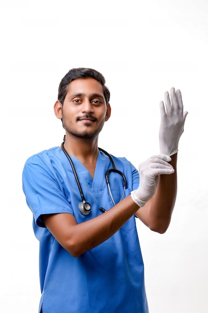 Jovem médico indiano calçando luvas protetoras, isoladas no fundo branco.