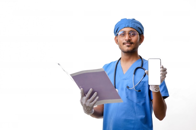 Jovem médico indiano mostrando a tela do smartphone sobre fundo branco.