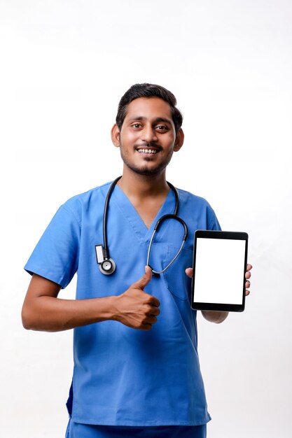 Jovem médico indiano mostrando a tela do tablet sobre fundo branco.