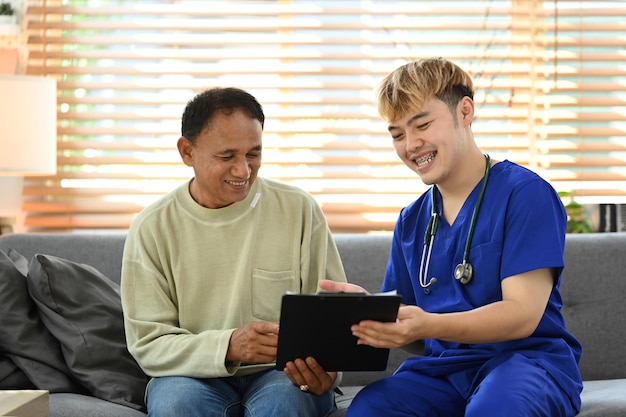 Jovem médico masculino compartilhando boas notícias de teste de saúde com um homem sênior feliz durante a visita domiciliar seguro médico conceito de saúde médica para idosos