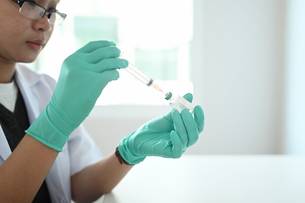 Jovem médico ou cientista segurando a vacina e a seringa de injeção.