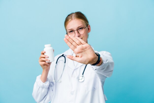 Jovem médico russo segurando o frasco de comprimidos azul fazendo um gesto de negação