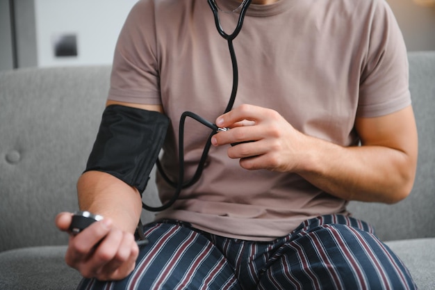 Jovem medindo sua pressão arterial em casa