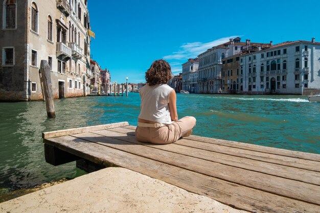 Jovem meditando de frente para os canais de veneza na itália