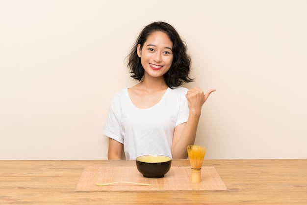 Jovem menina asiática com chá matcha com polegares para cima, porque algo de bom aconteceu