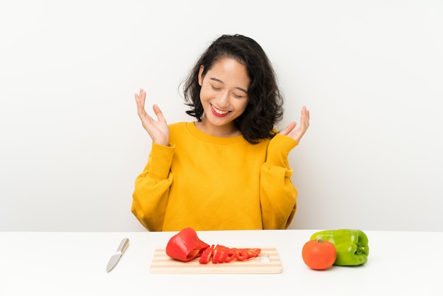 Jovem menina asiática com legumes em uma mesa rindo