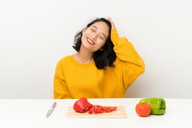 Jovem menina asiática com legumes em uma mesa rindo