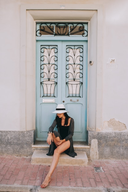 jovem menina bonita com chapéu posando contra o pano de fundo de uma porta vintage