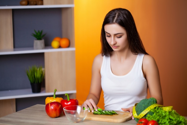 Jovem menina bonita prepara uma salada de dieta útil