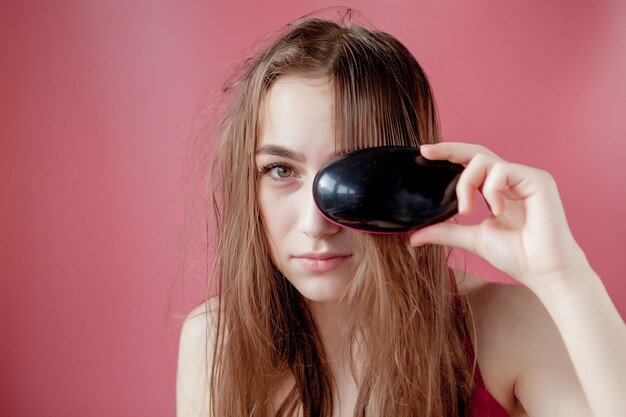 Jovem menina bonita tendo problemas enquanto cabelo na parede rosa