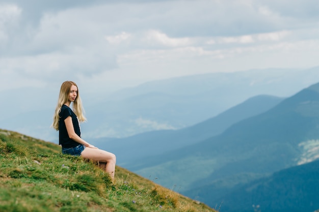 Jovem menina loira posando nas montanhas