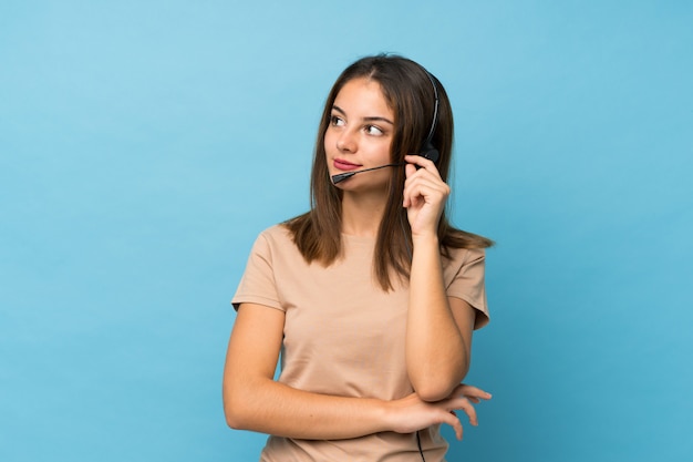 Jovem menina morena isolado azul trabalhando com fone de ouvido