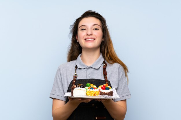 Jovem menina morena segurando mini bolos