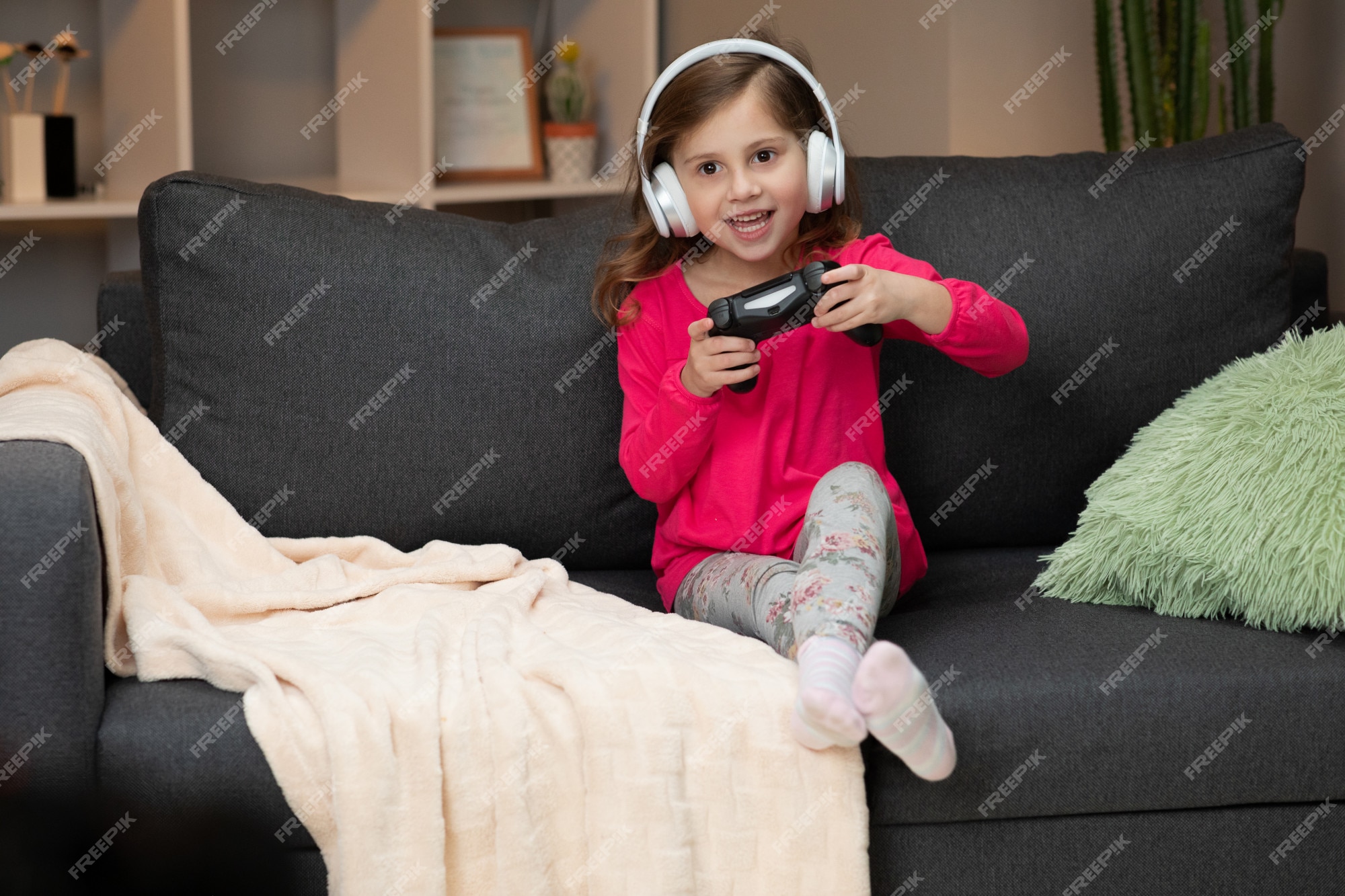 Jovem menina sentada no sofá jogando um vídeo na sala de estar em casa. mão  de menina gamer animado segurando o joystick jogando jogo de console usando  um controlador sem fio.