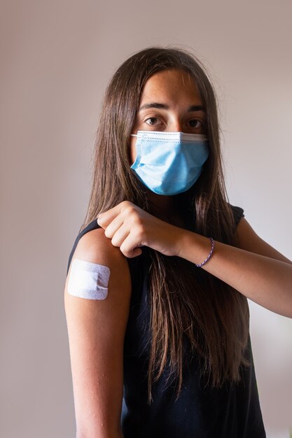 Foto jovem menina vacinada com curativo adesivo após a injeção. prevenção de covid de saúde e medicina