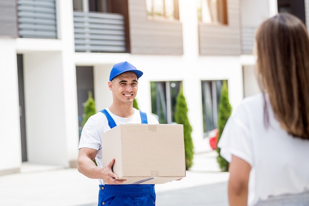 Jovem mensageiro entregando mercadorias para uma jovem em casa.