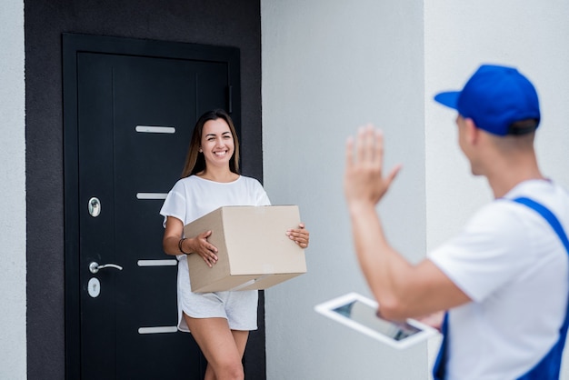 Jovem mensageiro entregando mercadorias para uma jovem em casa