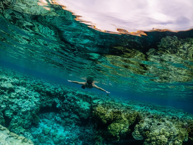 Jovem mergulhando em recifes de corais no mar tropical