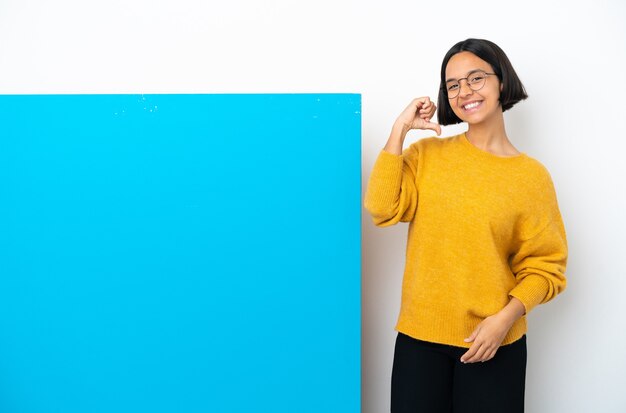 Jovem mestiça com um grande cartaz azul isolado no fundo branco, orgulhosa e satisfeita