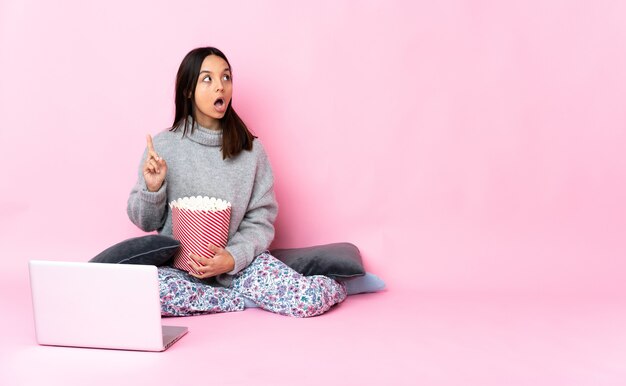 Jovem mestiça comendo pipoca enquanto assiste a um filme