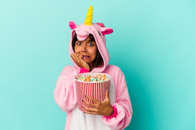 Jovem mestiça de pijama de unicórnio comendo pipoca