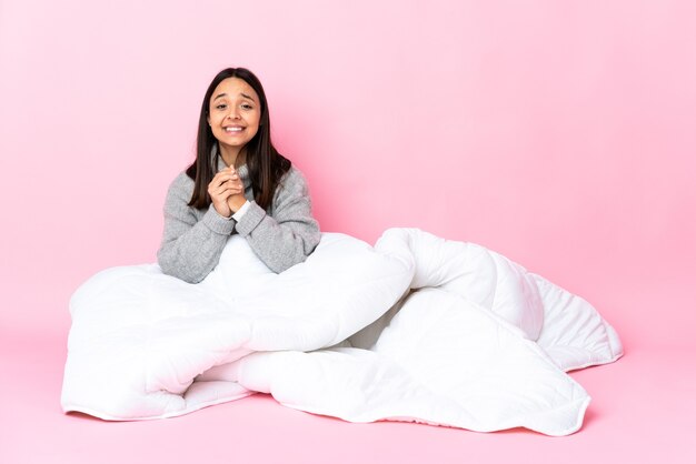 Jovem mestiça de pijama sentada no chão rindo